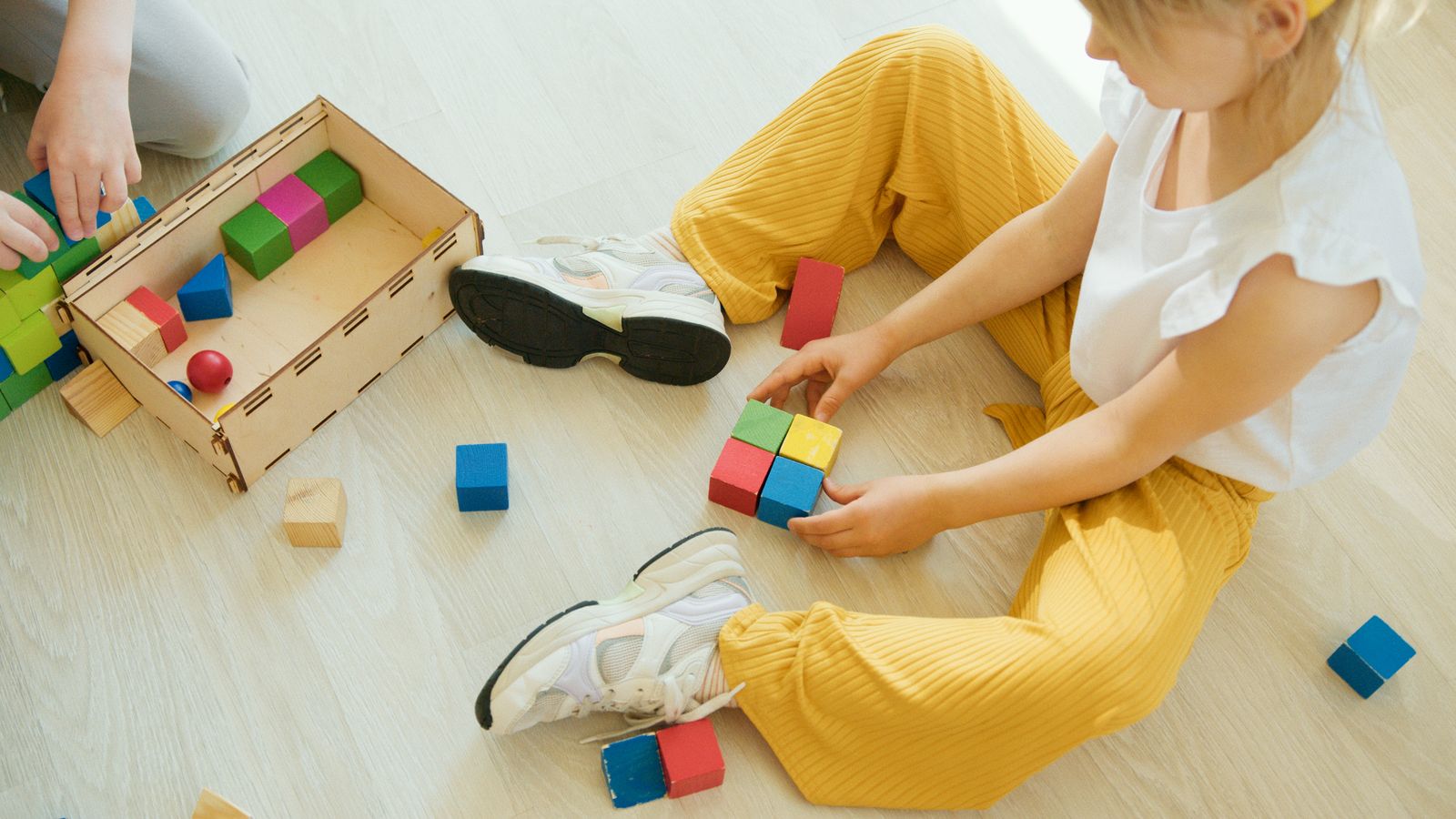Young child playing with colorful wooden blocks on the floor