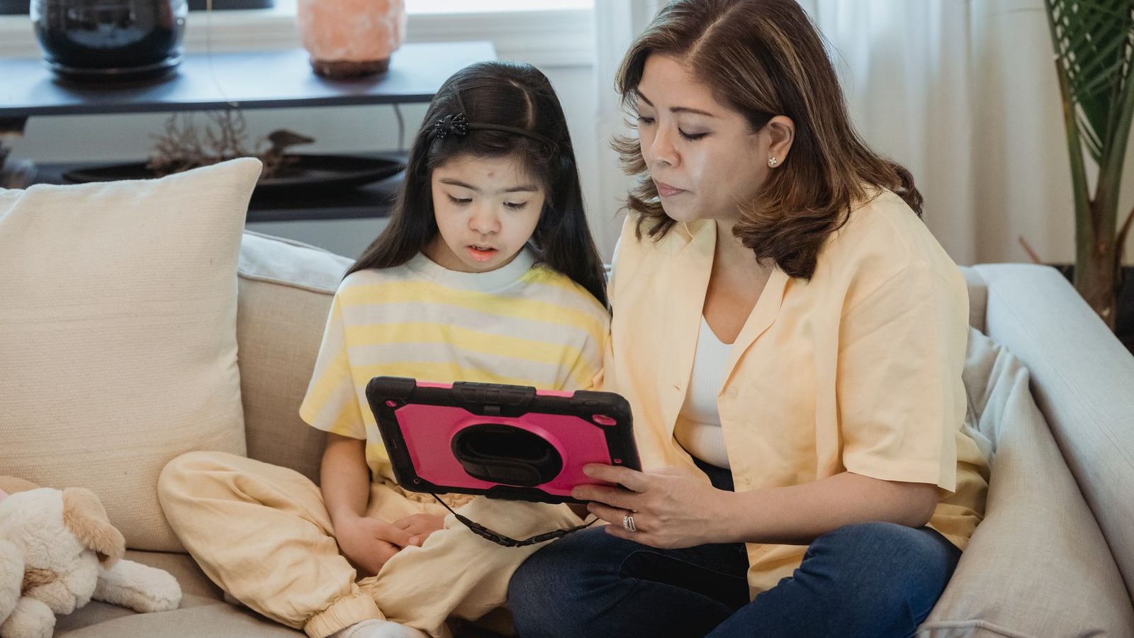 Parent and child using a tablet together on the sofa