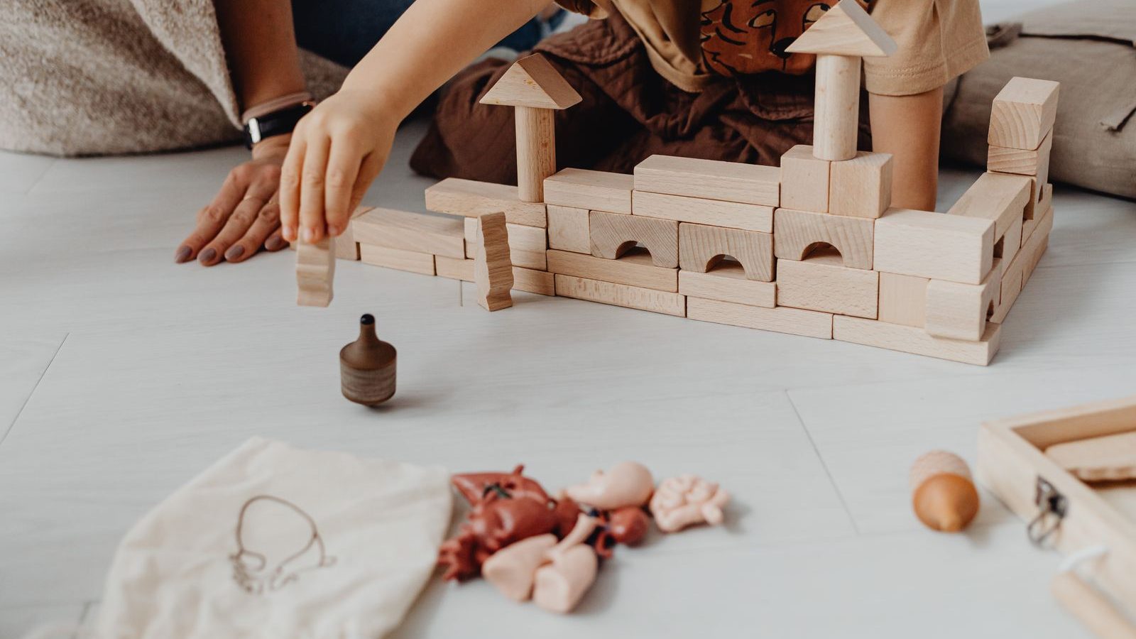 Child playing with wooden building blocks on the floor at home
