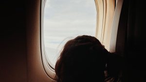 Young child seated by an airplane window during a flight
