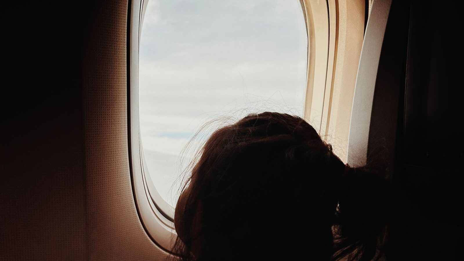 Young child seated by an airplane window during a flight
